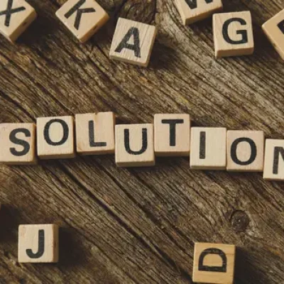 Blocs en bois formant le mot "solution" sur une table en bois, illustrant la recherche de réponses sur les mots clés.